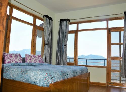a bedroom with a bed and large windows at Ridhi Sidhi cottage in Kīar