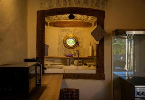 uma cozinha com um lavatório e um espelho na parede em CHEZ GUETOU Gîte de charme en Lozère em La Tieule