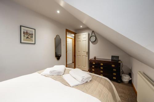 a bedroom with a bed with white sheets and a dresser at Aldo's Place in Dingwall