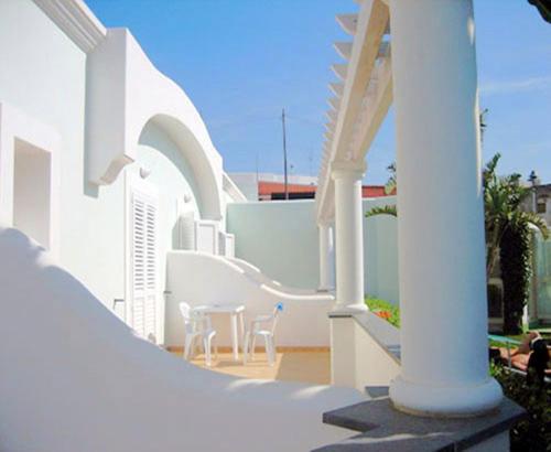 a white building with chairs and a table on a balcony at Hotel Albatros in Ischia