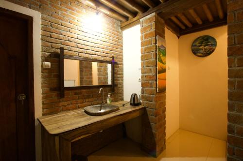 a bathroom with a sink and a brick wall at Mu Homestay in Tetebatu