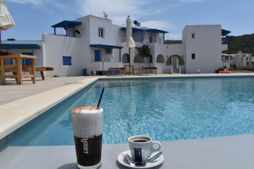 a drink sitting on a table next to a swimming pool at Amodari studios on the beach in Plaka