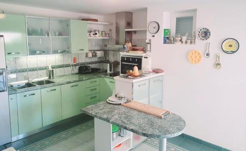 een keuken met groene kasten en een granieten aanrecht bij Red Hill Beach House - stunning 3-story residence in Zaboric