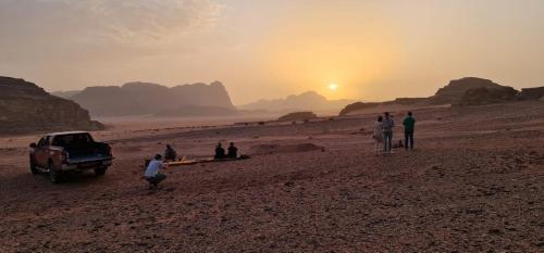 a group of people standing in the desert with a truck at Martian desert Camp in Wadi Rum