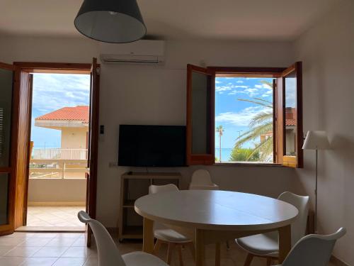 a dining room with a table and chairs and a tv at BeachFront Rooms Marina di Ragusa in Marina di Ragusa