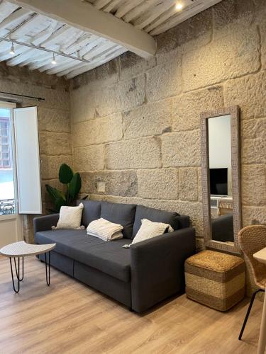 a living room with a couch and a stone wall at A Das Marias VINTAGE in Ourense