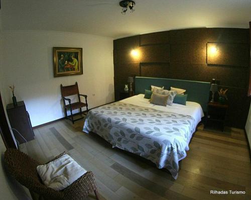 ein Schlafzimmer mit einem Bett und zwei Stühlen darin in der Unterkunft Rilhadas Casas de Campo in Fafe