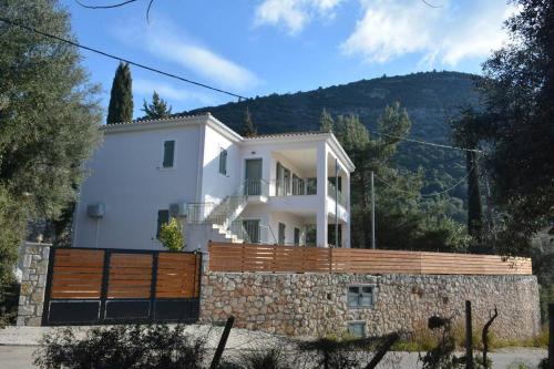 une grande maison blanche avec une clôture en bois dans l'établissement Sissy Villas 1, à Poros