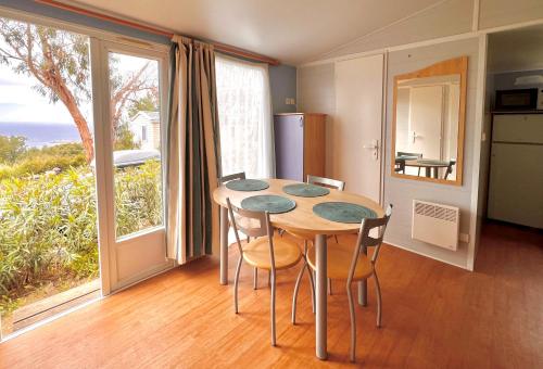 une salle à manger avec une table, des chaises et une grande fenêtre dans l'établissement Le Fango, à Lumio