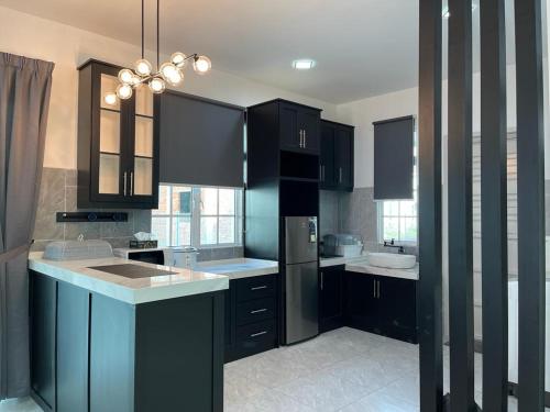 a kitchen with black cabinets and a refrigerator at De France Pool Villa Mu5lim Only in Malacca