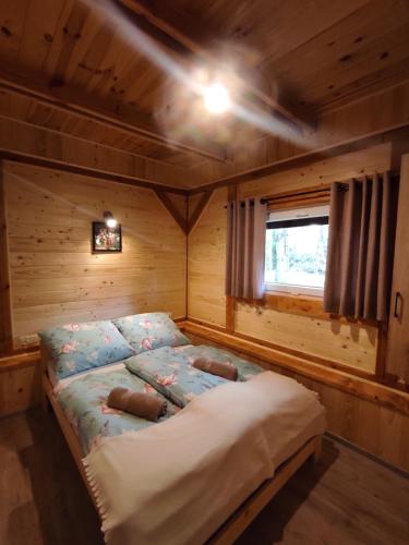 a bedroom with a bed in a wooden cabin at Dom Nad Stawem Krawno in Piecki