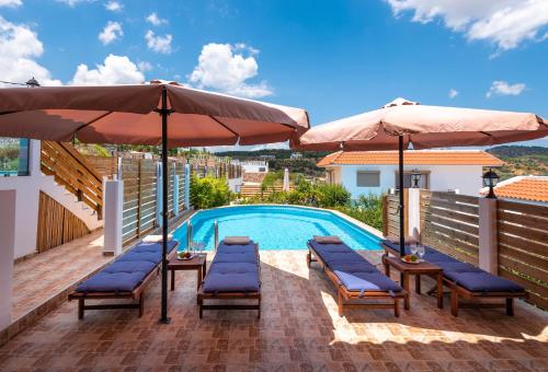 a swimming pool with two umbrellas and chairs and a swimming pool at Kolymbia Village in Kolimbia