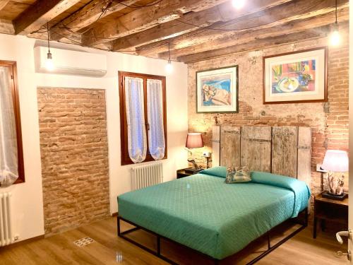 een slaapkamer met een groen bed en een bakstenen muur bij Old town Chioggia apartments in Chioggia
