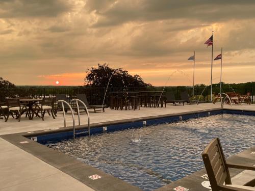 a swimming pool with tables and chairs and a sunset at PINEMARK Inn Suites Events in Saint Clair