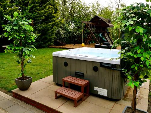 a hot tub with a bench next to a tree at Deluxe 2 Bed Versace Bungalow Hot Tub, Sky TV, Cinema Screen Saffron Walden in Saffron Walden