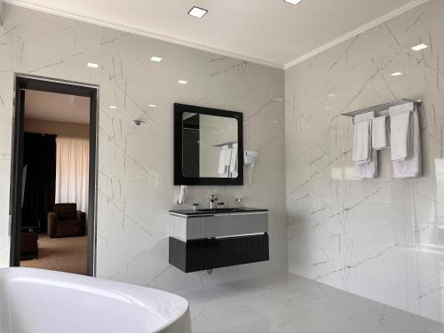 a white bathroom with a sink and a mirror at Astor Hotel in Samarkand