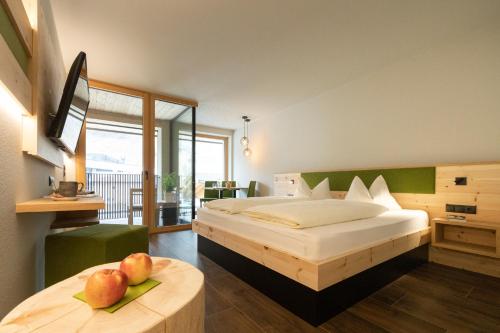 Hotel Maibad في فيبيتينو: غرفة نوم بسرير وطاولة عليها تفاح