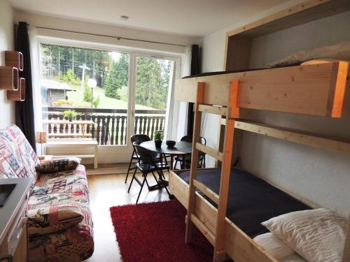 une chambre avec un lit superposé avec une table et un balcon dans l'établissement Studio ski au pied rénové, balcon, piscine, parking - FR-1-598-131, aux Gets