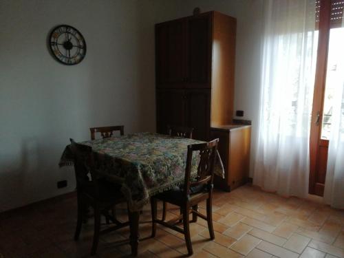 mesa de comedor con sillas y reloj en la pared en Appartamento Il Cedro en Rosia