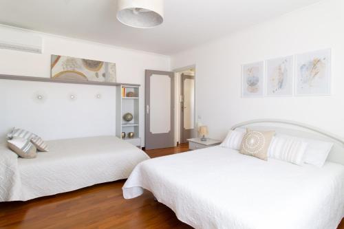 2 camas num quarto com paredes brancas e pisos em madeira em Attico Centralissimo Vista Mare em Torvaianica