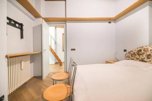 a bedroom with a white bed and two chairs at Casa Anita in Mergozzo