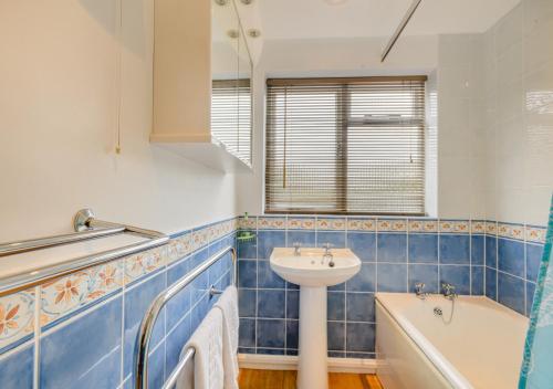 ein blau gefliestes Badezimmer mit einem Waschbecken und einer Badewanne in der Unterkunft 2 The Homestead in Frostenden