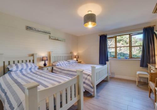 a bedroom with two beds and a window at Gorwel in Abersoch
