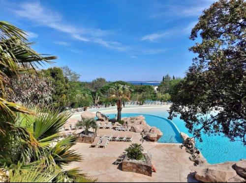 un complexe avec une piscine bordée de chaises et d'arbres dans l'établissement Appt Climatisé de charme-moderne - Vue Mer Club Vacances Restanques Golfe Saint-Tropez - Les Roses - Grimaud, à Grimaud