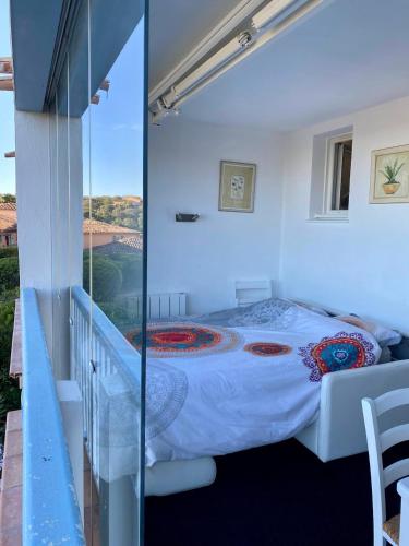 une chambre avec un lit et un balcon dans l'établissement Appt Climatisé de charme-moderne - Vue Mer Club Vacances Restanques Golfe Saint-Tropez - Les Roses - Grimaud, à Grimaud