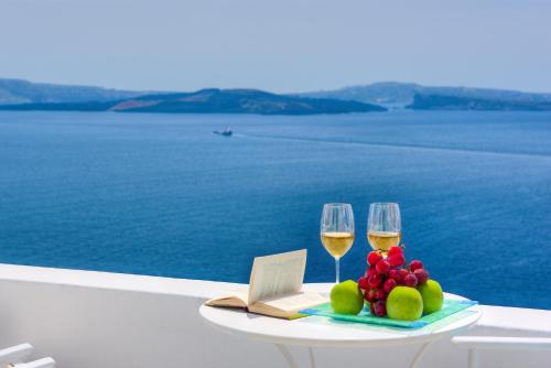 a table with two glasses of wine and fruit at Kima Oia Suites in Oia