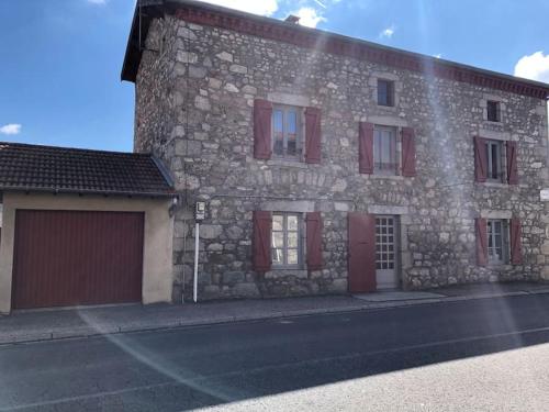 a stone building with red doors and a garage at Le Val Danse - Maison de caractère de 1870 - Rénovée en 2020 in Saint-Anthème