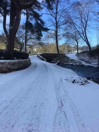 a snow covered road with footprints in the snow at Pendle Hill Barley 17th Century 2 bed-bath period cottage in Barrowford
