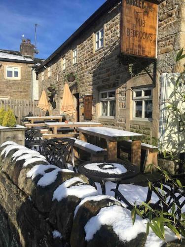 a stone building with a table and chairs in the snow at Pendle Hill Barley 17th Century 2 bed-bath period cottage in Barrowford