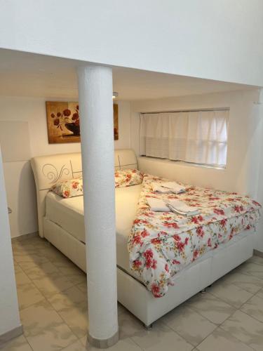 a white bedroom with a bed and a column at Du Port in Erlach
