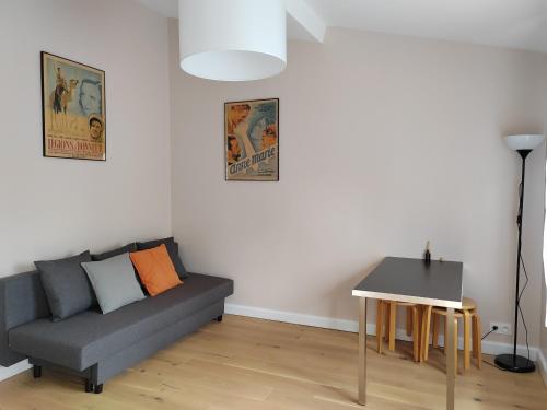 ein Wohnzimmer mit einem Sofa und einem Tisch in der Unterkunft Belle maison indépendante 4 pers avec terrasse in Rueil-Malmaison