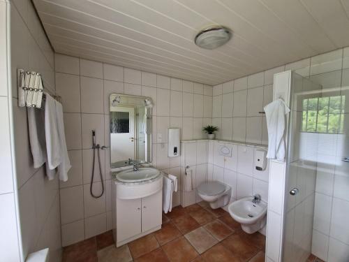Baño blanco con lavabo y aseo en Ferienhaus Heinz, en Heiligkreuzsteinach