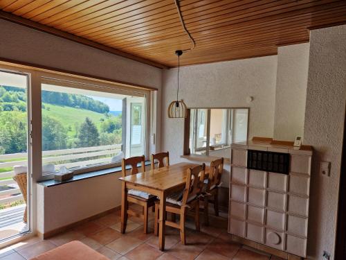 una sala da pranzo con tavolo, sedie e finestra di Ferienhaus Heinz a Heiligkreuzsteinach