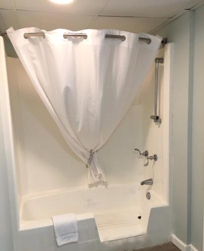 a bathroom with a shower with a white shower curtain at Ocean Plaza Motel in Myrtle Beach