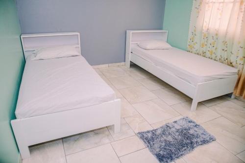 Habitación con 2 camas blancas y suelo de baldosa. en Happy Holidays Style Residences, en Paramaribo