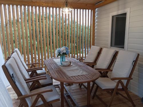 una mesa de madera con sillas y un jarrón de flores en un porche en Lado Mobile Home Croatia, Camp Oaza Lučica, Drage, en Drage