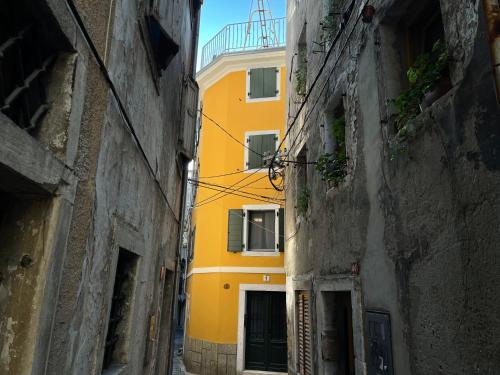 um edifício amarelo num beco entre dois edifícios em Apartments Piranom em Piran