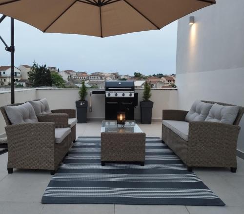 a patio with couches and a table and an umbrella at Ina's apartments in Lefkimmi