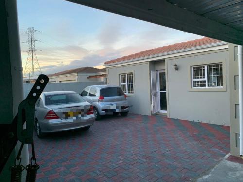 dos autos estacionados en un estacionamiento frente a una casa en Naliya Guest house en Ciudad del Cabo