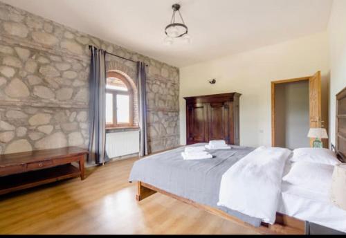 sypialnia z dużym łóżkiem i kamienną ścianą w obiekcie Elizbar Talakvadze Winery w mieście Kardanakhi