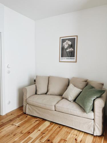 a couch in a living room with a wooden floor at powiew - adults only b&b pensjonat noclegi Świnoujście - Unterkunft Swinemünde - guesthouse tennis garden breakfast at baltic sea in Świnoujście