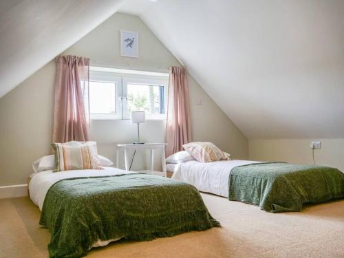 two beds in a attic room with a window at The Barn at Courtleigh in Kingsbridge