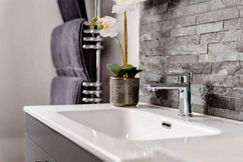 a bathroom with a white sink and a brick wall at Penthouse Suite, Central St Leonards, Sea View in St. Leonards