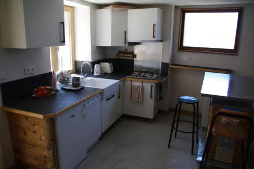 a small kitchen with white cabinets and a window at Appartement Dans Chalet de Montagne in Bozel