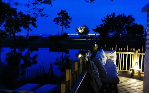 a bed on a deck next to a pond at night at Le Bungalow du Ferret - Mobil Home Premium in Claouey
