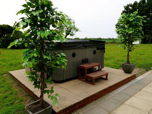 a shed with a bench next to two trees at Deluxe 4 5 Bed Hot Tub Cinema Room 15 in Saffron Walden